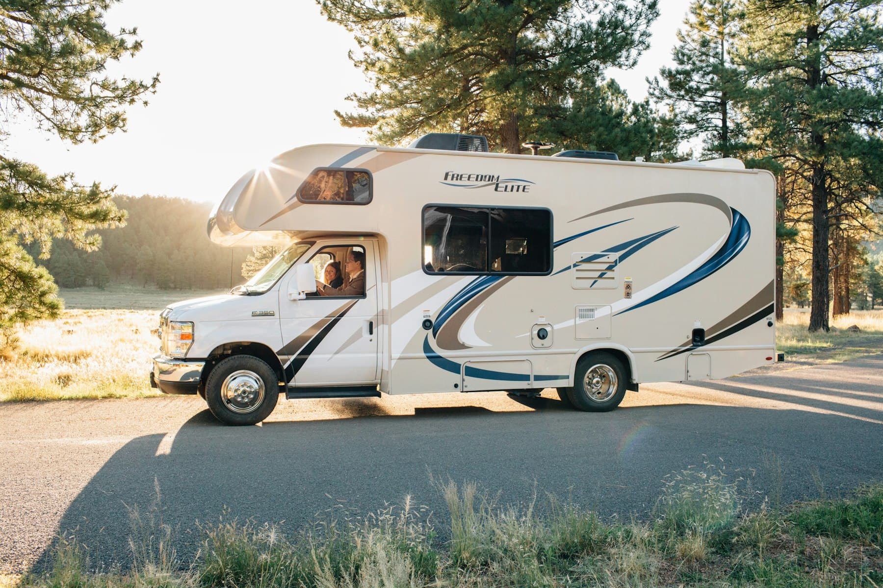 A white and brown camper van travels an open two-lane highway